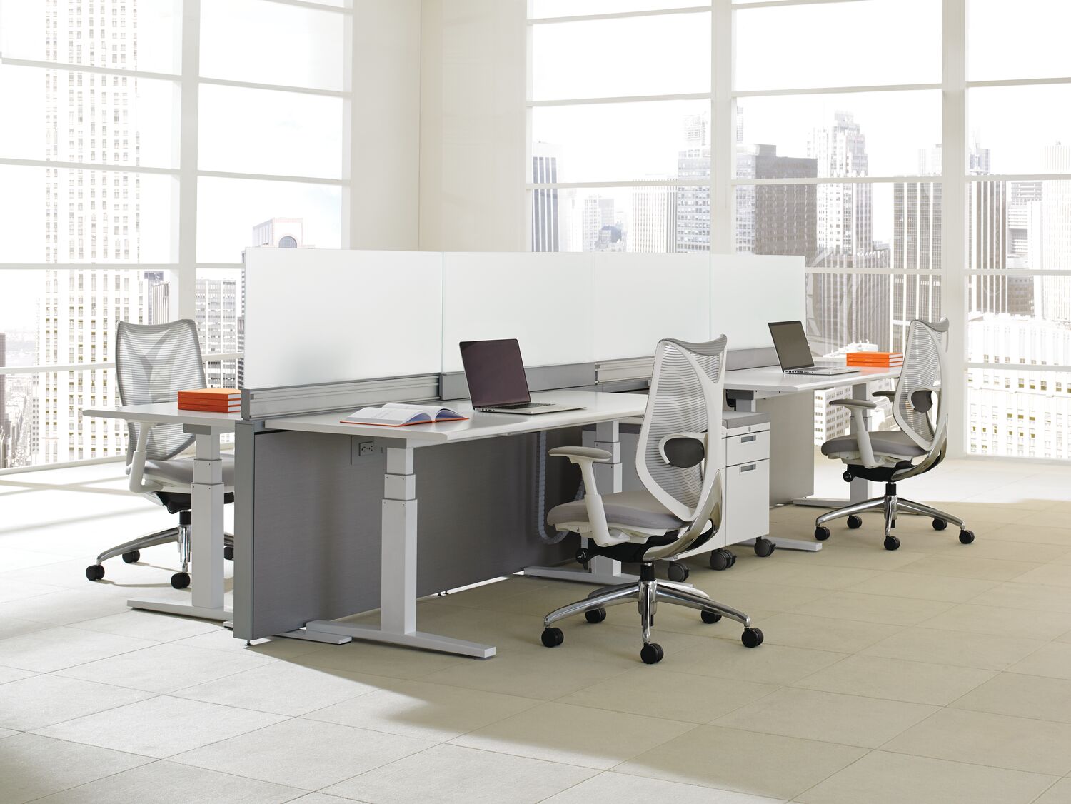Modern office setup with desks, chairs, and large windows showing a cityscape.
