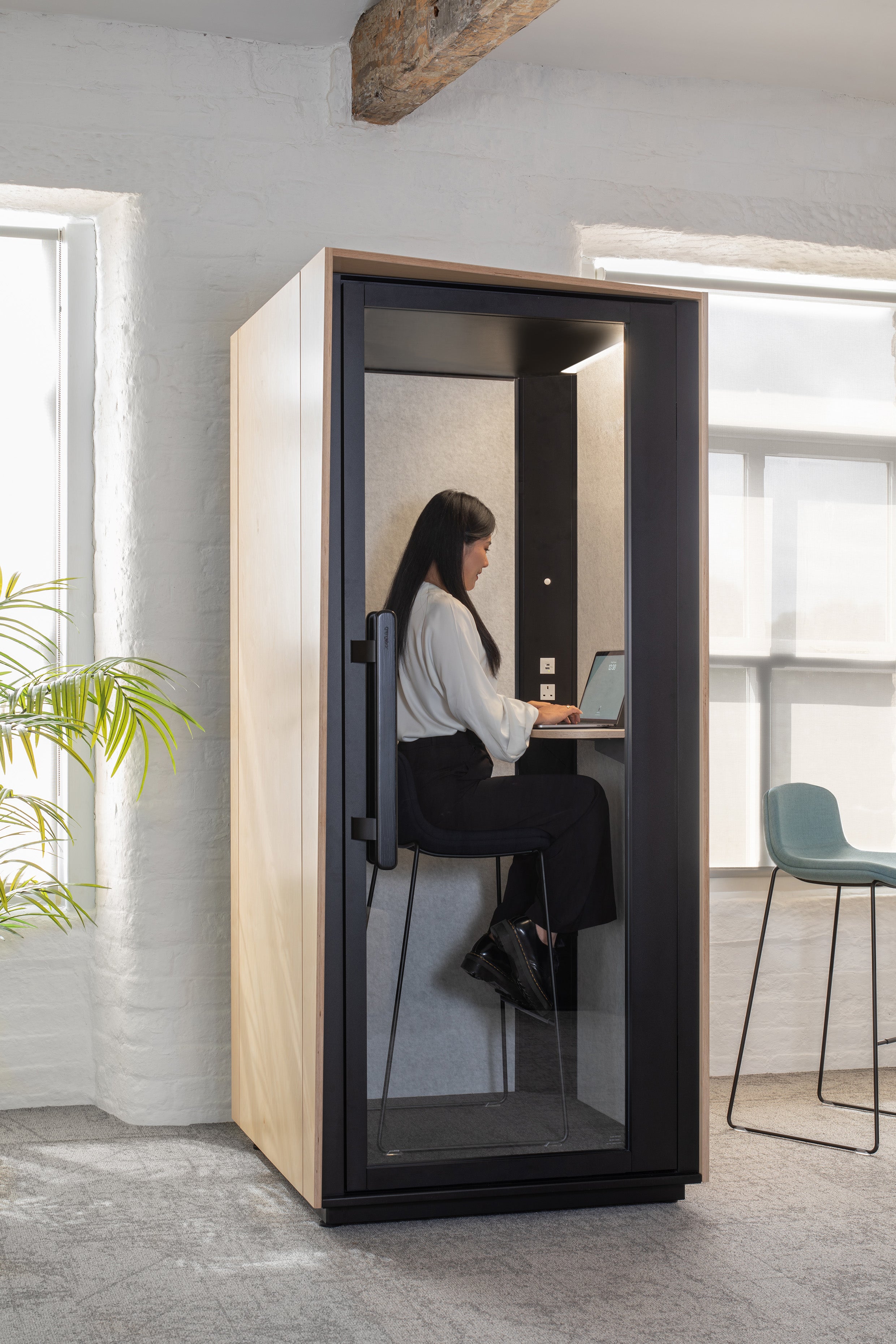 Person using a small office pod in a modern office setting
