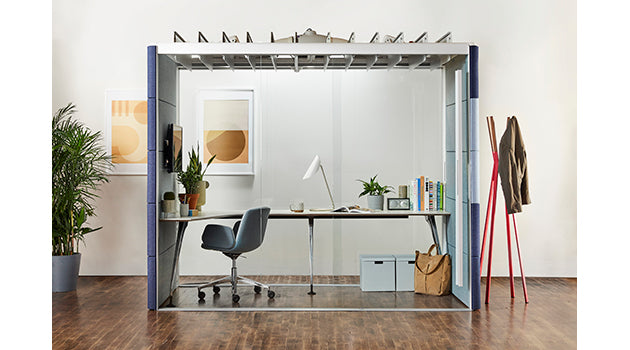 Modern office space with a desk, chair, and office supplies enclosed by a transparent partition. rent furniture